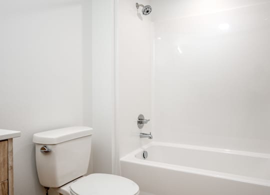 A white toilet sits next to a white bathtub in a bathroom.