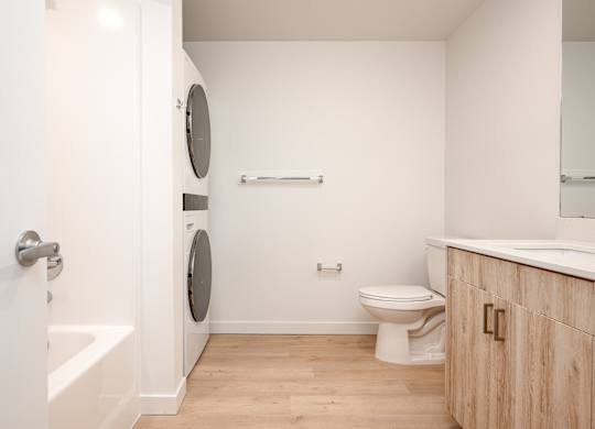 A white bathroom with a toilet, a tub, and a mirror.