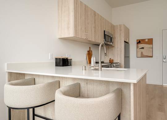 A kitchen with a white countertop and two chairs.