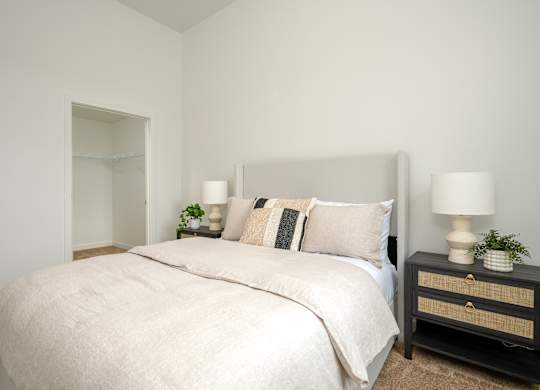 A bedroom with a large bed and two lamps on bedside tables.