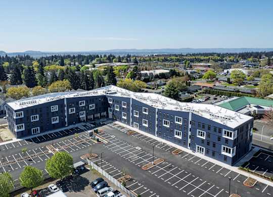 A large grey building with a parking lot in front.