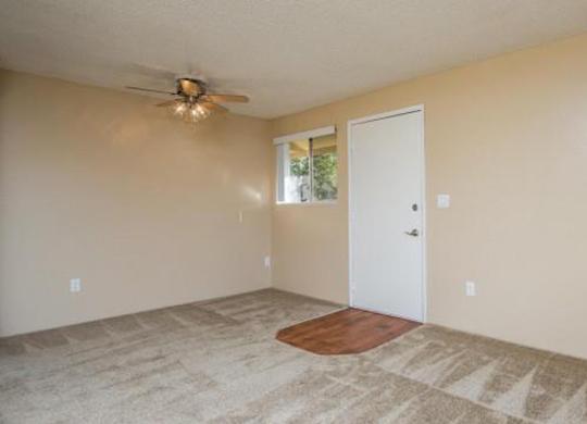A room with a ceiling fan and a door leading to a balcony.