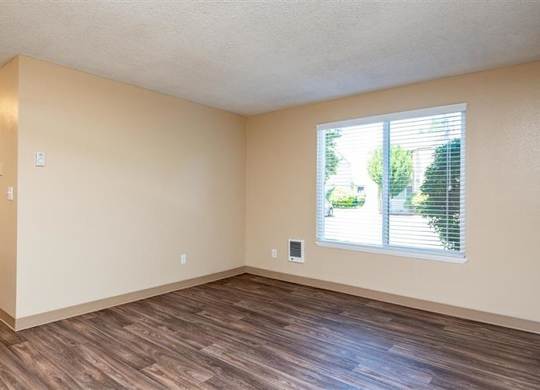 A room with wooden floors and a window with blinds.