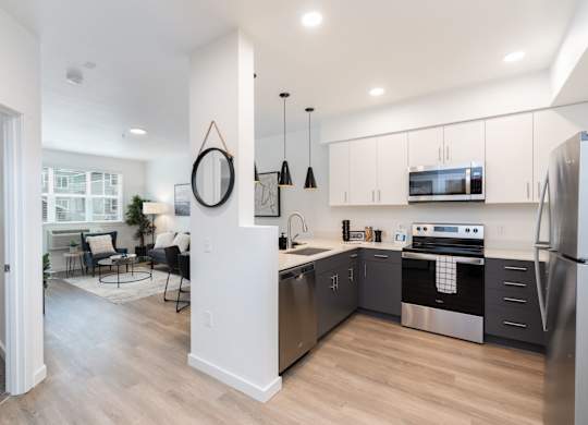 A modern kitchen with stainless steel appliances and a dining area with a round mirror.
