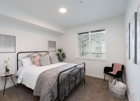 A bedroom with a bed, chair, and a window with blinds.