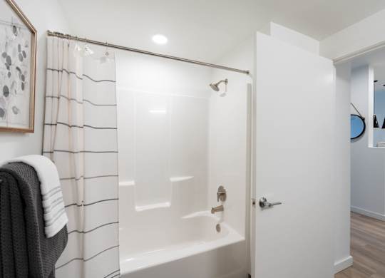 A white bathroom with a shower and a towel hanging on the side.