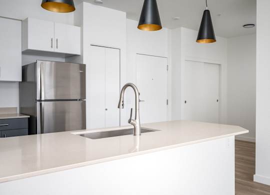 A modern kitchen with a stainless steel refrigerator and a white countertop.