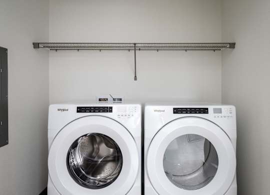 Two white Whirlpool washing machines in a laundry room.
