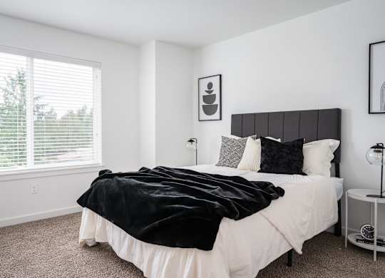 A bedroom with a large bed and a window with blinds.