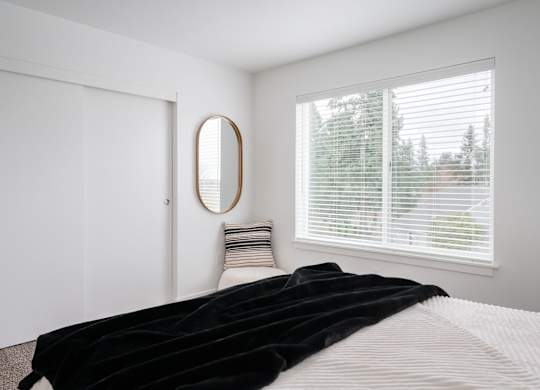 A bedroom with a large bed and a round mirror on the wall.