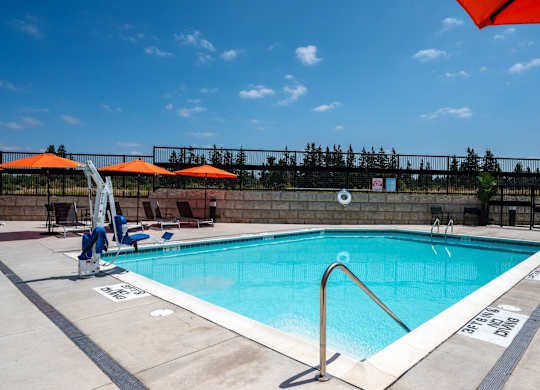 A swimming pool with a blue water and white poolside.