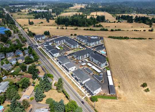 A large building complex is surrounded by a road and a field.