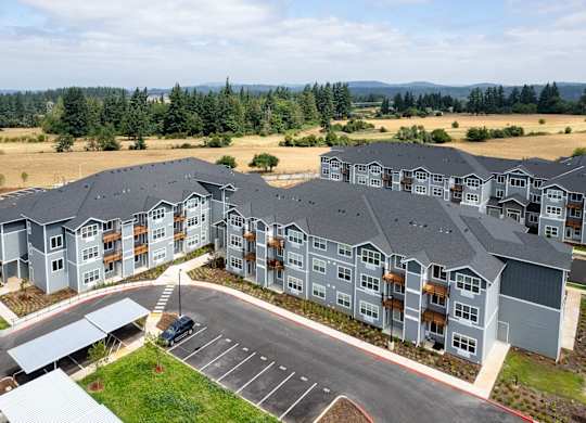A large apartment complex with a parking lot in front.