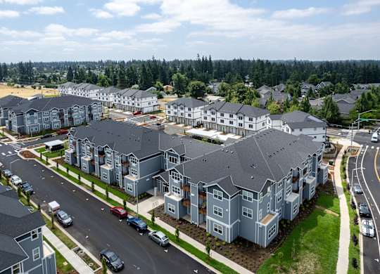 A large residential complex with multiple buildings and cars parked in front.