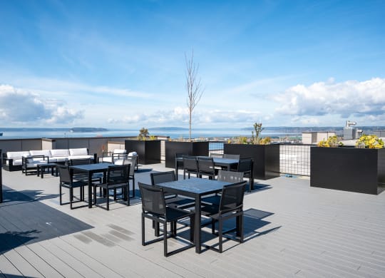 a rooftop patio with tables and chairs overlooking the ocean