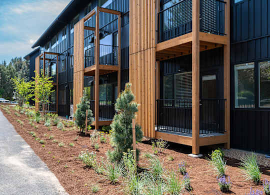 A modern building with a black exterior and wooden balconies.