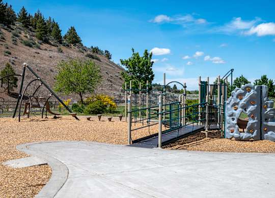 A playground with a slide, swings, and climbing wall.