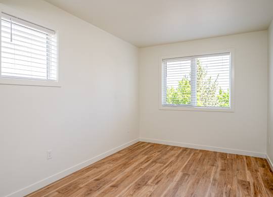 A room with wooden floors and two windows.