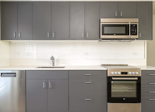 A kitchen with a stainless steel refrigerator, a microwave, and a stove top oven.