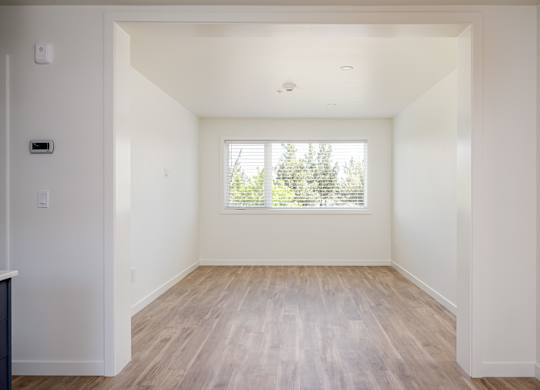 A room with a window and wooden flooring.