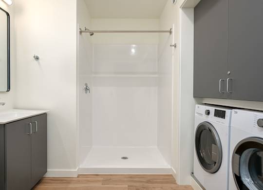 A modern bathroom with a washer and dryer built into the cabinetry.