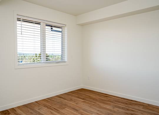 A room with a window and wooden flooring.