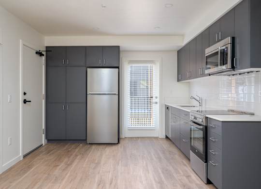 A kitchen with a refrigerator, oven, and microwave.