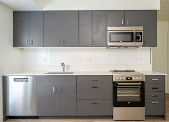 A modern kitchen with a stainless steel refrigerator, a double oven, and a microwave above the sink.
