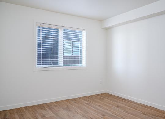 A room with a window and wooden flooring.