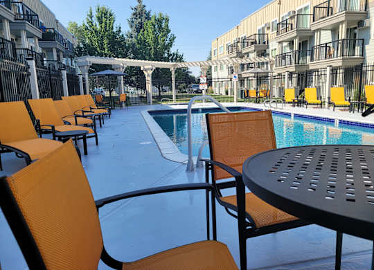 a poolSunset Apartments | Outdoor Seasonal Poolside patio with chairs and tables at an apartment building