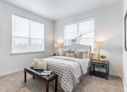 A bedroom with a large bed and a nightstand with a lamp.