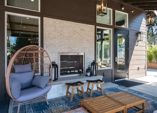 A modern outdoor patio with a hanging chair, a fireplace, and a wooden coffee table.