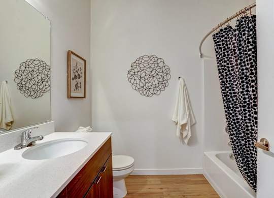 A bathroom with a white sink and a black and white shower curtain.