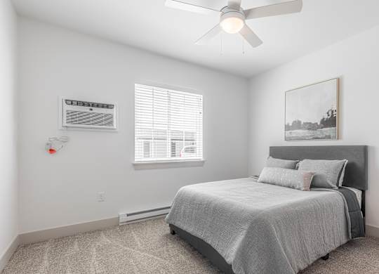 A bedroom with a bed, a window with blinds, a ceiling fan, and a painting on the wall.