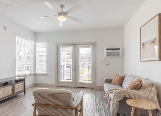 A living room with a grey couch, a wooden chair, and a ceiling fan.