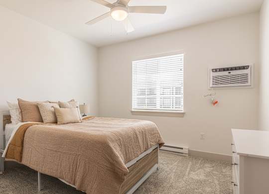 A bedroom with a bed, nightstand, and window.