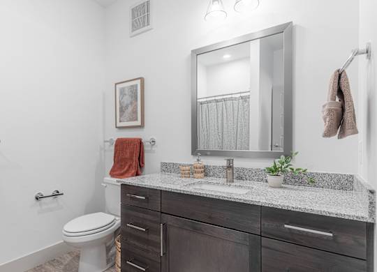 A bathroom with a toilet, sink, and a mirror.