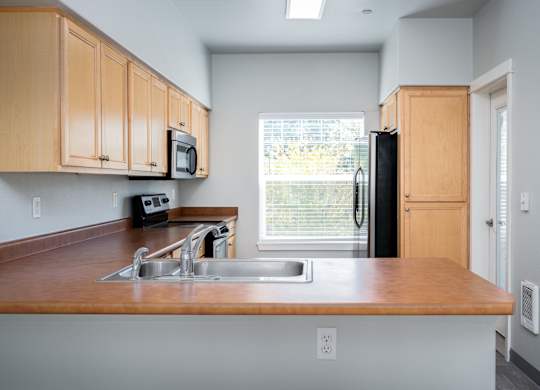 A kitchen with wooden cabinets and a black refrigerator.
