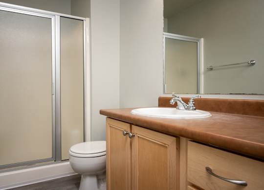 A bathroom with a toilet, sink, and mirror.