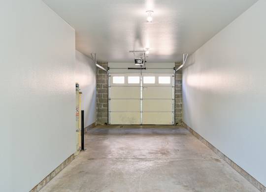 A large, empty room with a concrete floor and white walls.