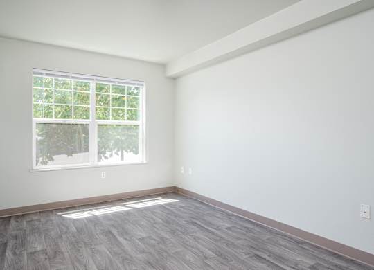 A room with a window and wooden flooring.