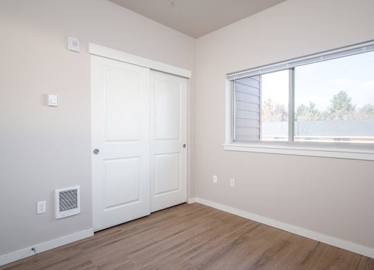 an empty bedroom with a window and a door