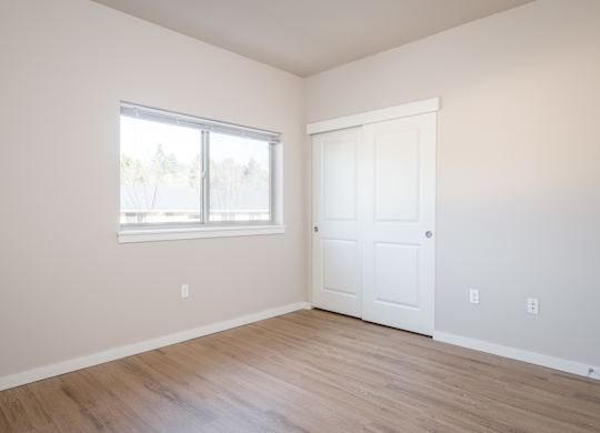 an empty room with white walls and a window and wooden floors
