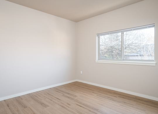 an empty room with wooden floors and a window
