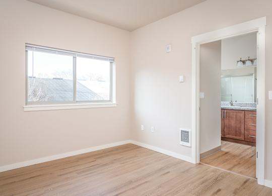 an empty bedroom with a large window and a bathroom