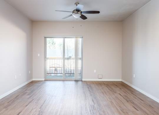 an empty living room with wooden floors and a ceiling fan