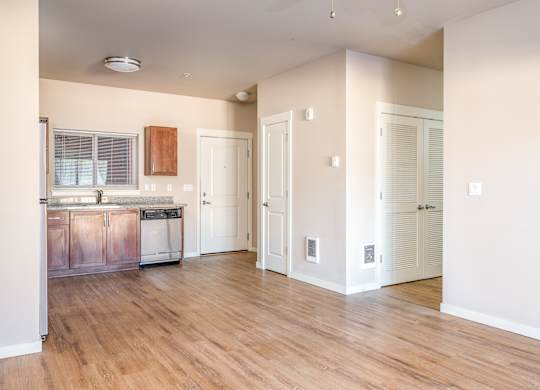 an empty kitchen and living room with wood flooring and white walls