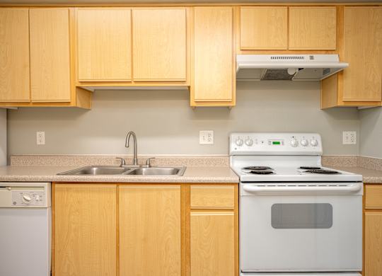 A kitchen with a white stove and wooden cabinets.