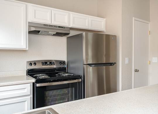 A modern kitchen with a stainless steel stove, oven, and refrigerator.