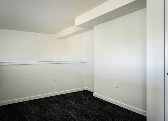 loft space with white walls and dark hardwood flooring